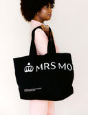 A model holding The Marquee Tote bag, featuring bold branding and a stylish design, perfect for everyday use.