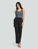 Woman wearing the Iconic Scoop Neck Tank Bodysuit in black sequin print, paired with tailored black pants for a stylish look.