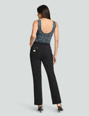 Woman wearing the Iconic Scoop Neck Tank Bodysuit in black sequins with tailored pants, showcasing a stylish back view.