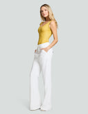Model wearing yellow scoop neck tank bodysuit paired with white wide-leg pants, showcasing comfort and style.