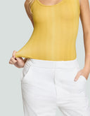 Model showcasing the Iconic Scoop Neck Tank Bodysuit in yellow, paired with white pants for a stylish look.