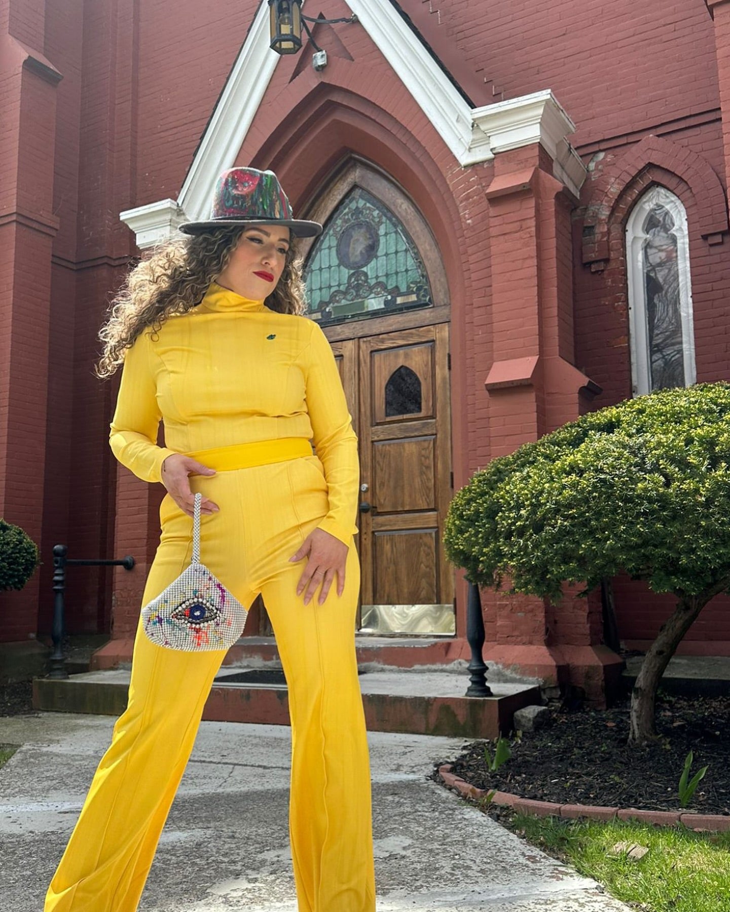 Stylish woman in Milano poses outside a church, showcasing fashion and vibrant colors in a sunny setting.