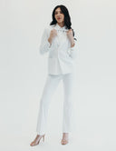 Model showcasing 'Meet Me At Noon' all-white suit with high-waisted pants and oversized blazer, exuding corporate elegance.