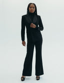 Chic all-black jumpsuit with oversized tuxedo jacket and structured puff shoulders, perfect for glamorous occasions.